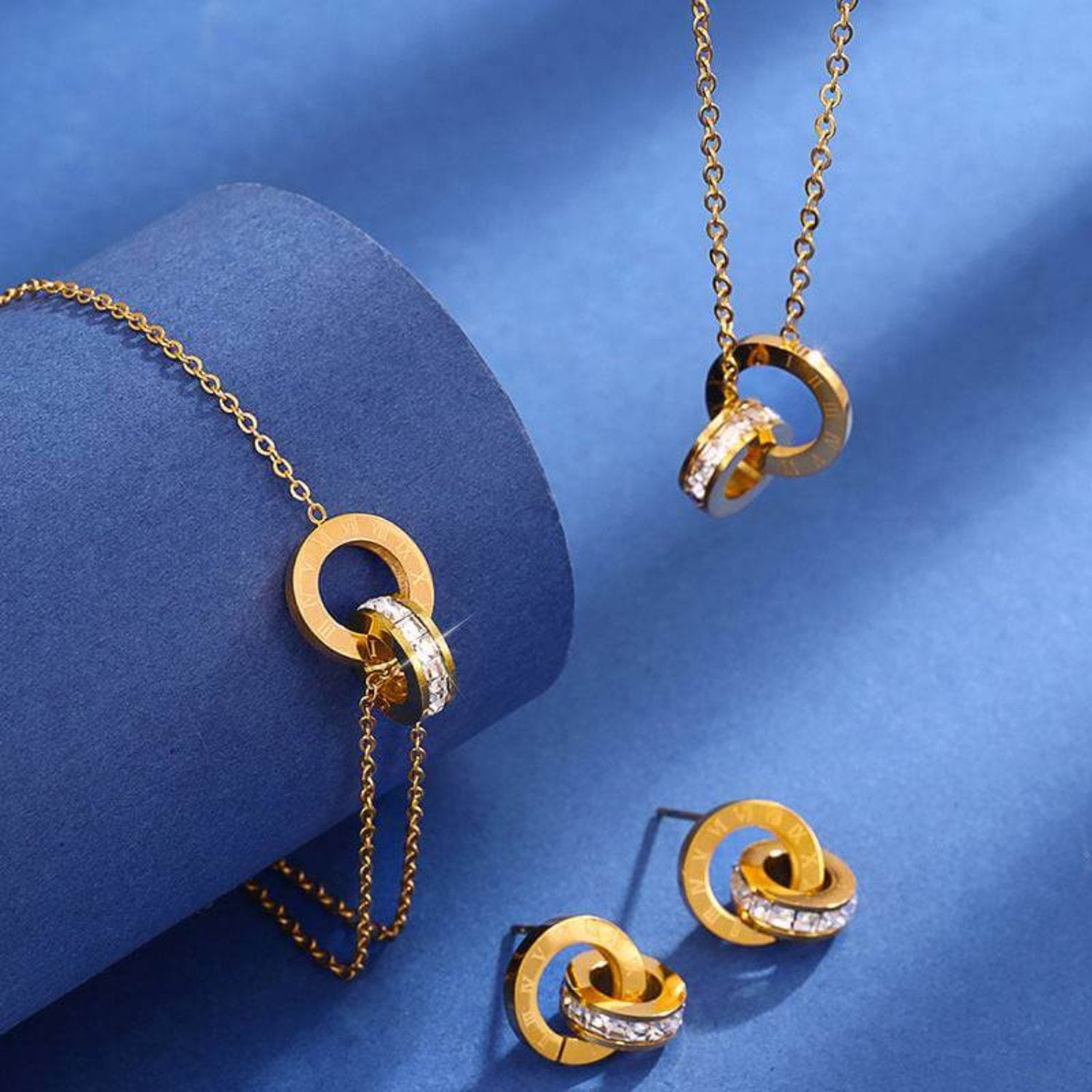 Three-piece jewelry set featuring a gold bracelet, necklace, and ear studs